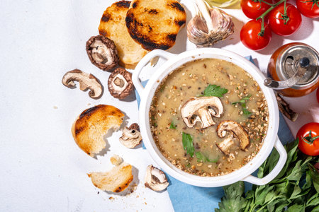 Homemade mushroom cream soup, with grilled champignons, cheese, greens and croutons, on white kitchen table copy spaceの写真素材