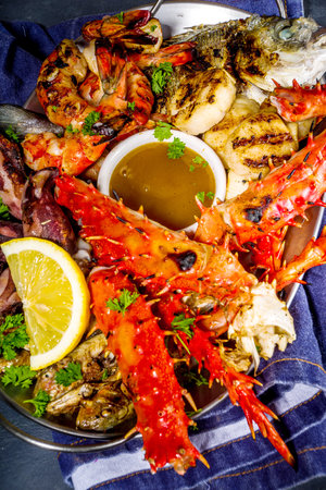 Assortment various barbecue Mediterranean grill food - fish, octopus, shrimp, crab, seafood, mussels, summer diet bbq party fest, with kebab, sauces, black concrete background, above copy spaceの写真素材