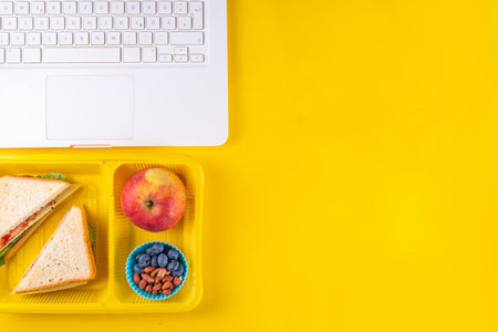 Healthy school meal, children packed lunch box with fruit, berry, nuts and sandwich with vegetables. Kids diet snack food with education school supplies, bright blue background top view copy spaceの写真素材