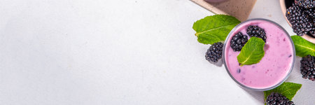 Two glasses of blackberry smoothie, yogurt or milkshake with fresh berry, mint leaves on white table background copy spaceの写真素材