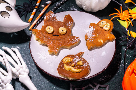Halloween creative kids breakfast. Cute homemade pancakes in the shape of Halloween holiday symbols - bat, jack pumpkin, ghost, made by cookie cuttingsの写真素材