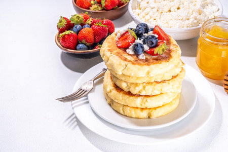Sweet homemade cottage cheese pancakes, american version of syrniki or cottage cheese fritters, big pan fried cheesy pancakes with fresh summer blueberry and strawberry, healthy high-protein breakfastの写真素材