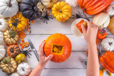 Preparation for Halloween with carving cutting pumpkin Jack Lantern. Female, woman and kids hands in frame, decorate, drawing and carves scary Halloween party Pumpkin top view copy spaceの写真素材