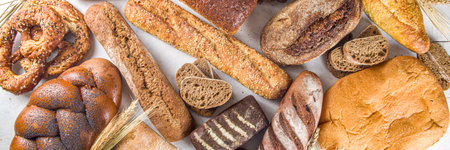 Assortment of various delicious freshly baked bread, on white background top view copy space