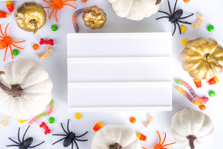 Happy Halloween day background. Flat lay with sweets and decorations for kids party, bucket pack with spiders, candy sweets, bat, on white table copy space top view frameの写真素材