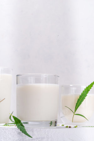 Cannabis milk. Non-dairy lactose free vegan milk from hemp seeds, on white background of cannabis leaves, industrial use of marijuana. Legal use of hemp product concept.の写真素材