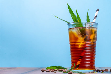 Medical cannabis hemp cold coffee drink. Glass of iced espresso coffee with cannabis oil drops and leaf drawn top , with hemp leaves and coffee beans, copy spaceの写真素材