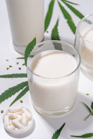 Cannabis milk. Non-dairy lactose free vegan milk from hemp seeds, on white background of cannabis leaves, industrial use of marijuana. Legal use of hemp product concept.の写真素材