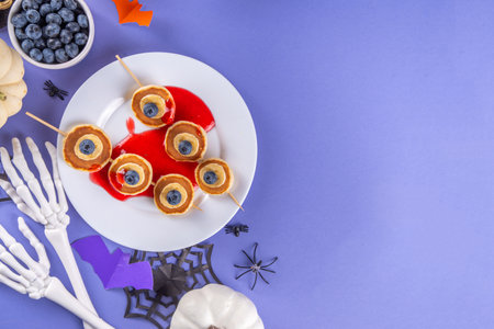 Funny kids breakfast for Halloween. Creative homemade sweet pancakes in form of traditional Halloween monsters and symbols, with fresh berry, chocolate and red syrupの写真素材