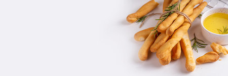 Italian Mediterranean grissini  bread sticks, with aromatic oil and sprigs of rosemary, on a white...