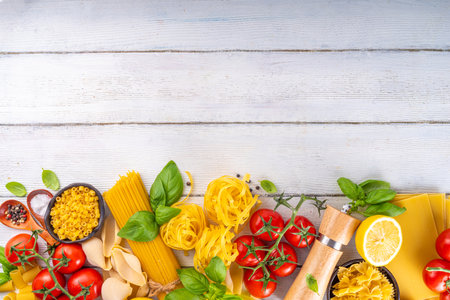 Various pasta with spices and ingredients for cooking. Preparation dinner, lunch background with fresh basil, tomatoes, spices, garlic and different sort and types of italian Mediterranean pastaの写真素材