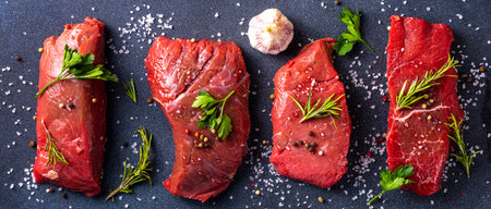 Cooking food background. Various cuts of raw fresh veal, beef, red meat with spices, rosemary, salt, pepper, garlic, olive oil, top view copy spaceの写真素材