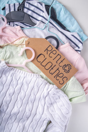 Clothing rental services background, with various woman, man, kids clothes for rent. Circular fashion, zero waste sustainable lifestyle concept, on white background with shopping tagの写真素材