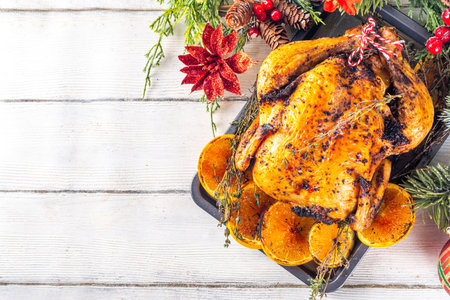 Christmas and Thanksgiving traditional baked chicken. Whole roasted chicken for holiday dinner, with oranges and thyme, on Christmas or Thanksgiving decorated tableの写真素材