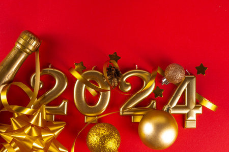 Happy new year 2024 greeting card background with gold numbers, champagne bottle, serpentine, Christmas and New Year decorations on red background copy spaceの写真素材