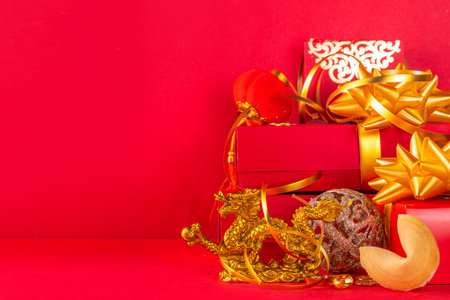 Chinese New Year 2024 greeting card. Bright red asian year of the dragon background with golden dragon figurine, Chinese lanterns, traditional jewelry, gifts, coins, cookies with wishes, copy spaceの写真素材