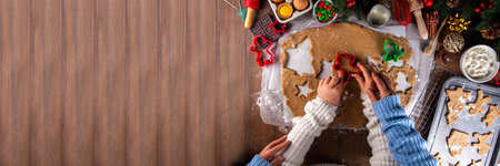 Cooking Christmas cookies family background. Mother and daughter hands top view on cozy wooden background, making gingerbread biscuits with cookie cutters, with New Year Christmas decorationの写真素材