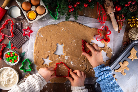 Cooking Christmas cookies family background. Mother and daughter hands top view on cozy wooden background, making gingerbread biscuits with cookie cutters, with New Year Christmas decorationの写真素材