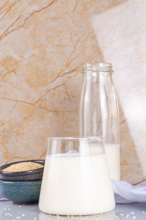 Black and white sesame milk, Alternative vegan non-dairy milk drink on glass and bottles with sesame seeds on light stone background. Raw food, vegetarian natural organic food dietの写真素材