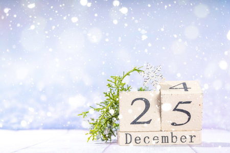 Simple minimal Christmas card background. Block wooden calendar with Christmas Day, december 24 and 25 on light snowy festive blurred lights background copy spaceの写真素材