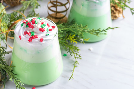 Green matcha Christmas latte with whipped cream and sugar sprinkles, on xmas New year holiday decorated backgroundの写真素材