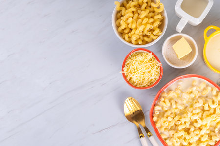 Creamy mac and cheese with ingredients for cooking. Macaroni pasta, bechamel cream sauce, milk,...
