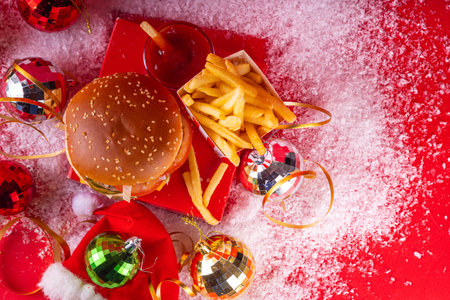 Christmas burger and french fries delivery menu. Big cheeseburger with french fries and ketchup sauce on festive Christmas and New Year decorated backgroundの写真素材