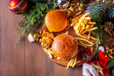 Christmas burger and french fries delivery menu. Big cheeseburger with french fries and ketchup sauce on festive Christmas and New Year decorated backgroundの写真素材