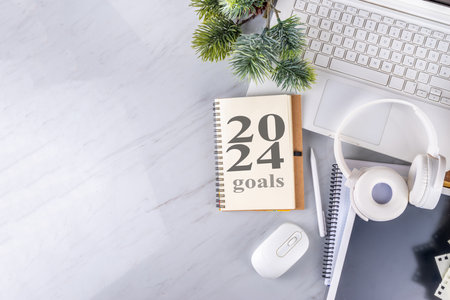 2024 goals and plans background. Blank notebook with laptop, pen, christmas tree background, on white marble office work table surface, top view copy spaceの写真素材