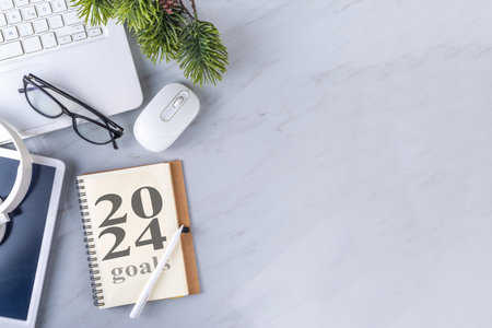 2024 goals and plans background. Blank notebook with laptop, pen, christmas tree background, on white marble office work table surface, top view copy spaceの写真素材