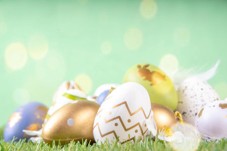 Easter egg and grass background. Funny colorful Easter eggs with bunny rabbit decor and sunny bokeh...
