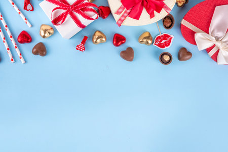 Valentine day celebration, invitation greeting card background with heart shape red, gold candy and chocolate sweets, gift box and on light blue background top view with copy spaceの写真素材