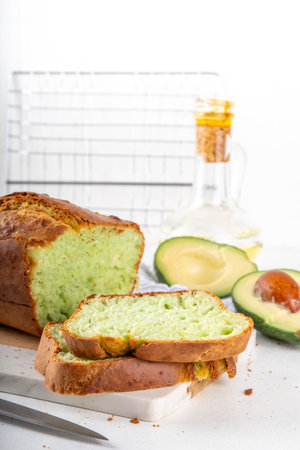 Homemade avocado loaf of bread, keto diet recipe, healthy alternative food idea, on white kitchen background with fresh avocado, copy spaceの写真素材