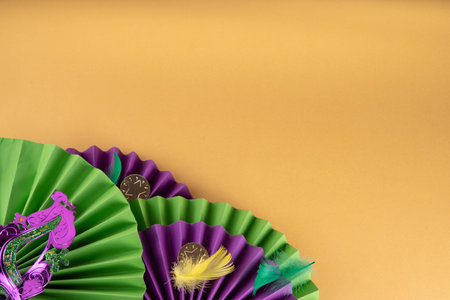 Mardi Gras colorful holiday greeting card background with festival masquerade accessories, decor, carnival mask, beads, feathers, fan on bright background traditional yellow purple green colorsの写真素材