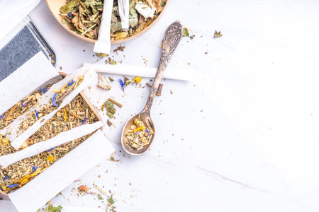 Alternative healthy berbal smoking blend. Handmade craft cigarette, preparation process, with mixture of herbs, leaves and flowers, with boxes, paper, on white backgroundの写真素材
