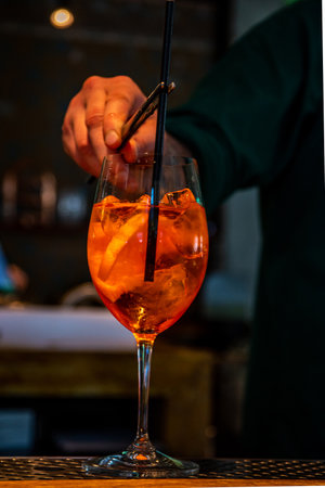 Realistic photo, close-up view of professional bartender in bar making cocktail in a tall glass, with ice and alcohol, male hands in pictureの写真素材