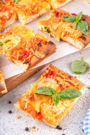 Rectangular homemade margarita pizza with tomatoes and basil, with ingredients and olive oil on white kitchen table backgroundの写真素材