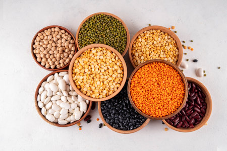 Various dried  beans, lentils, mung, chickpea, pea  assortment in wooden bowls. Legumes on white...