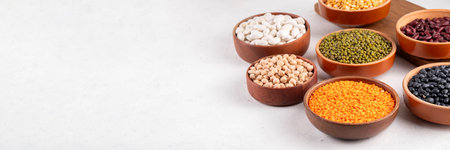 Various dried  beans, lentils, mung, chickpea, pea  assortment in wooden bowls. Legumes on white...