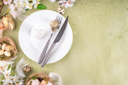Easter table setting with spring flora, plate, knife and fork with Easter eggs and nests on...