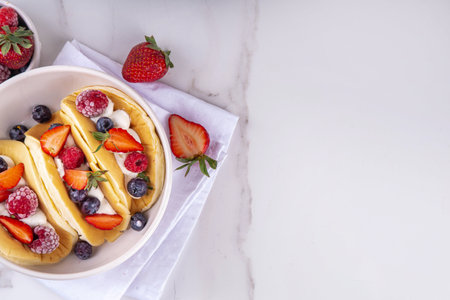 Pancake tacos. Portion of sweet dessert taco made with pancake, whipped cream, cottage cheese or ice cream, fruit and berries. Summer breakfast or brunch recipe, copy spaceの写真素材