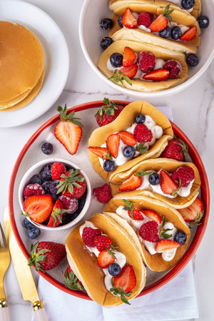 Pancake tacos. Portion of sweet dessert taco made with pancake, whipped cream, cottage cheese or ice cream, fruit and berries. Summer breakfast or brunch recipe, copy spaceの写真素材