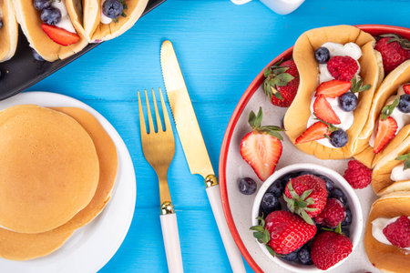 Pancake tacos. Portion of sweet dessert taco made with pancake, whipped cream, cottage cheese or ice cream, fruit and berries. Summer breakfast or brunch recipe, copy spaceの写真素材