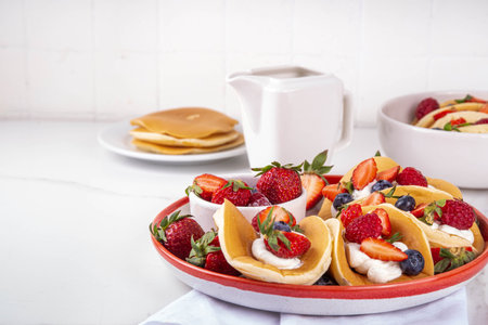 Pancake tacos. Portion of sweet dessert taco made with pancake, whipped cream, cottage cheese or ice cream, fruit and berries. Summer breakfast or brunch recipe, copy spaceの写真素材