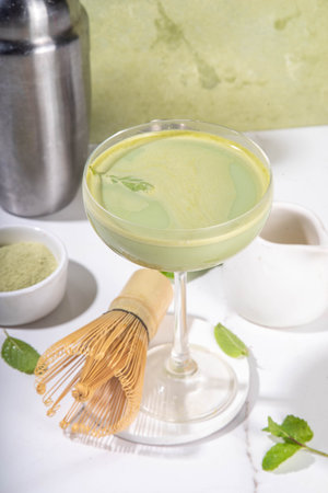 Creamy matcha martini cocktail Matchatini, trendy cold summer cocktail. Matcha non-alcohol mocktail or alcohol cocktail,  in martini glasses with green matcha powder, with hard light backgroundの写真素材