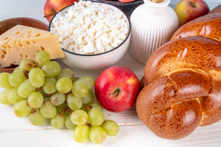 Happy Shavuot holiday background with summer red apples, wheat, grapes, dairy products - cheese,...