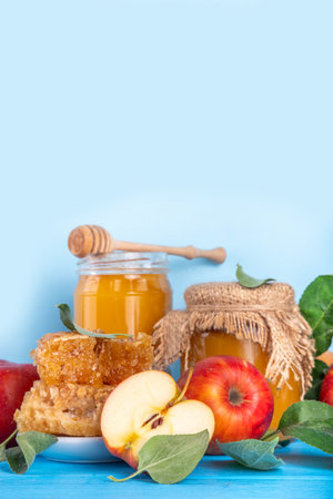 Jewish holiday Rosh Hashanah or apple feast day concept, with red apples, apple leaves, honey in jar and honeycombs light blue wooden background copy space aboveの写真素材