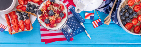 USA patriotic breakfast or brunch with american flag decorated oatmeal, layered yogurt granola dessert, toast sandwiches with fresh berries, and coffee cup on kitchen garden tableの写真素材