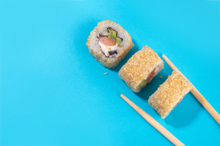 Creative  Japanese seafood sushi set background containing sushi rolls, maki, gunkans with chopsticks on high-colored bright blue backgroundの写真素材