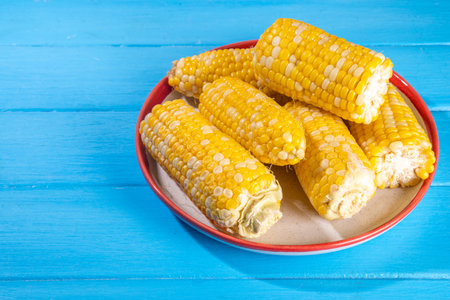 Sweet boiled corn cobs portions on plate, copy space